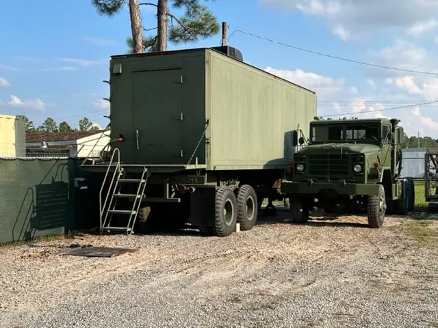 Sleeping quarters trailer with entry stairs beside a truck