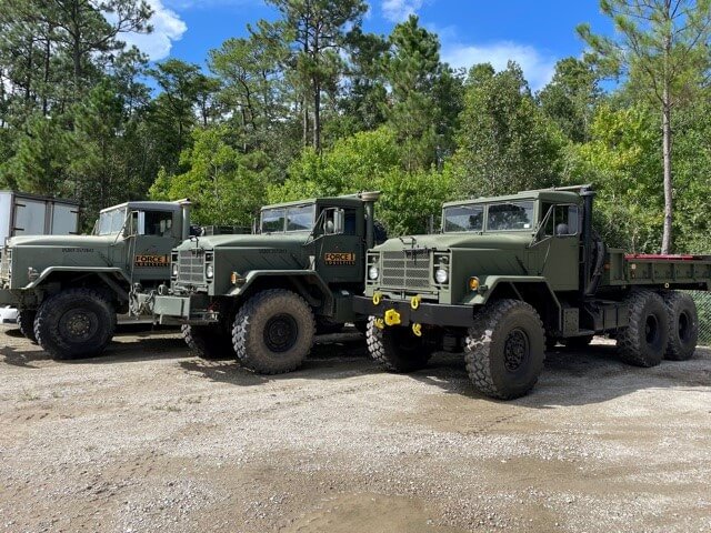 Three Force 1 Logistics six-wheel trucks parked side by side
